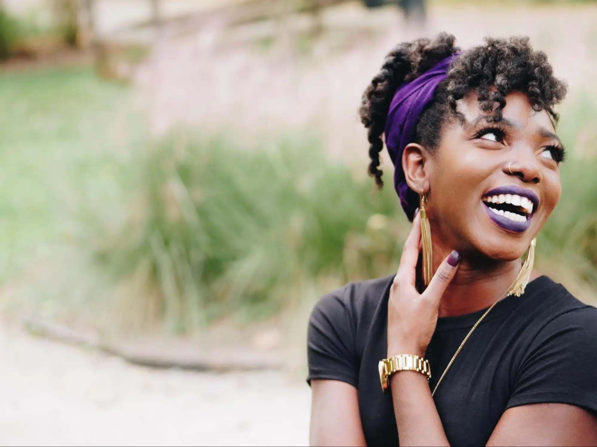 Black woman laughing wearing purple lipstick