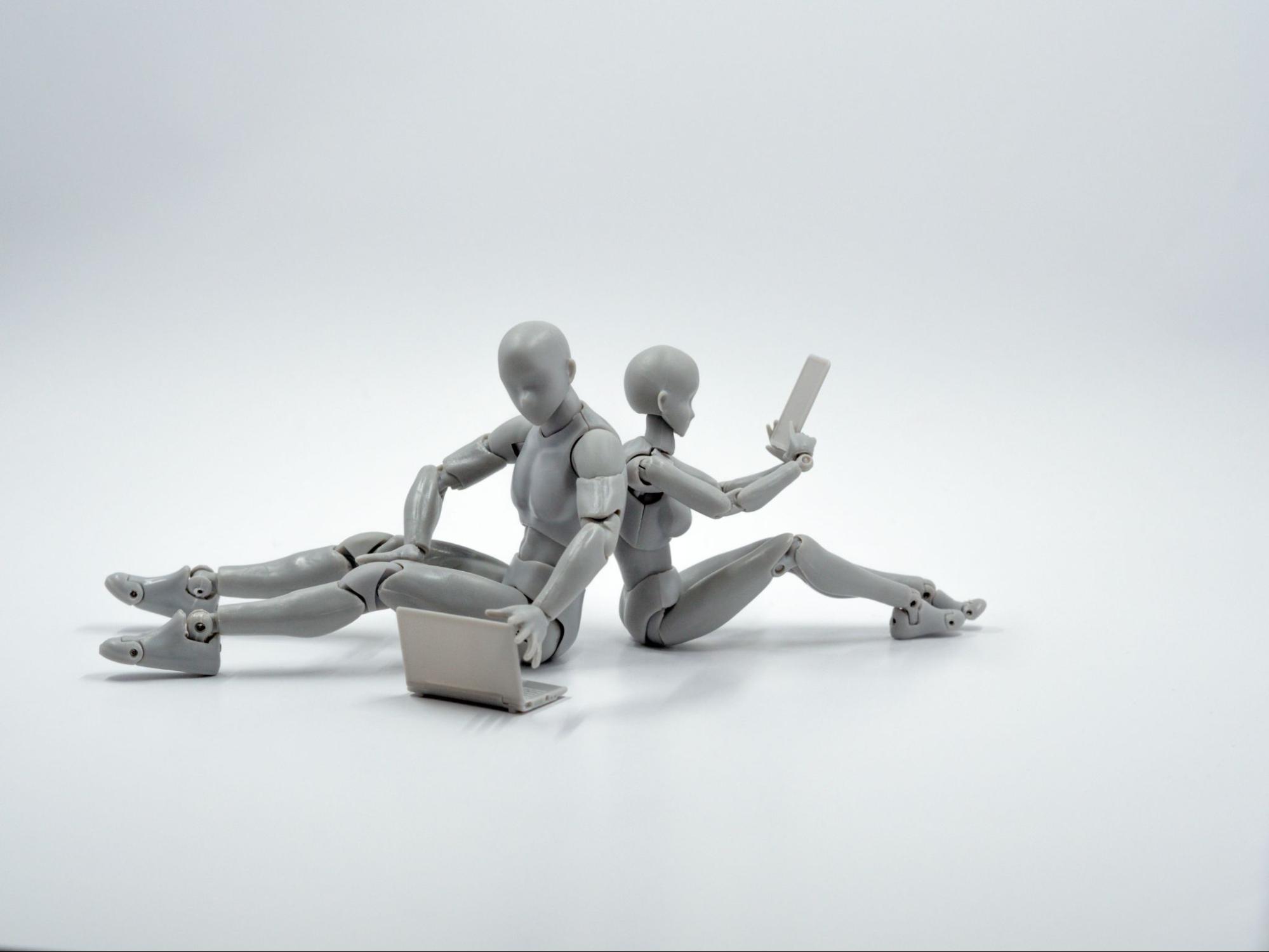 Two human-like figurines sitting on the floor